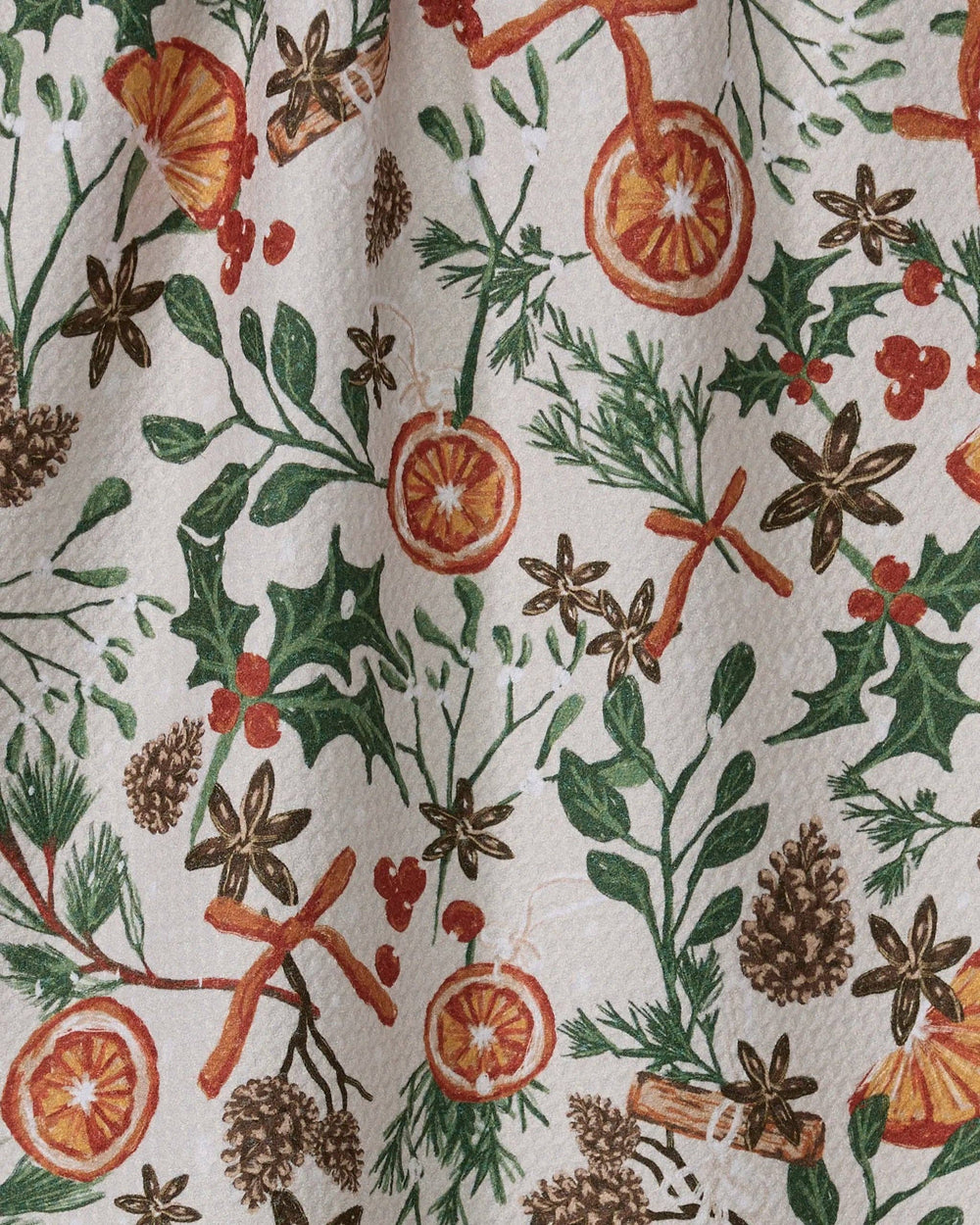 Geometry Canela Tea Towel featuring citrus slices, cinnamon sticks, pinecones and winter greenery